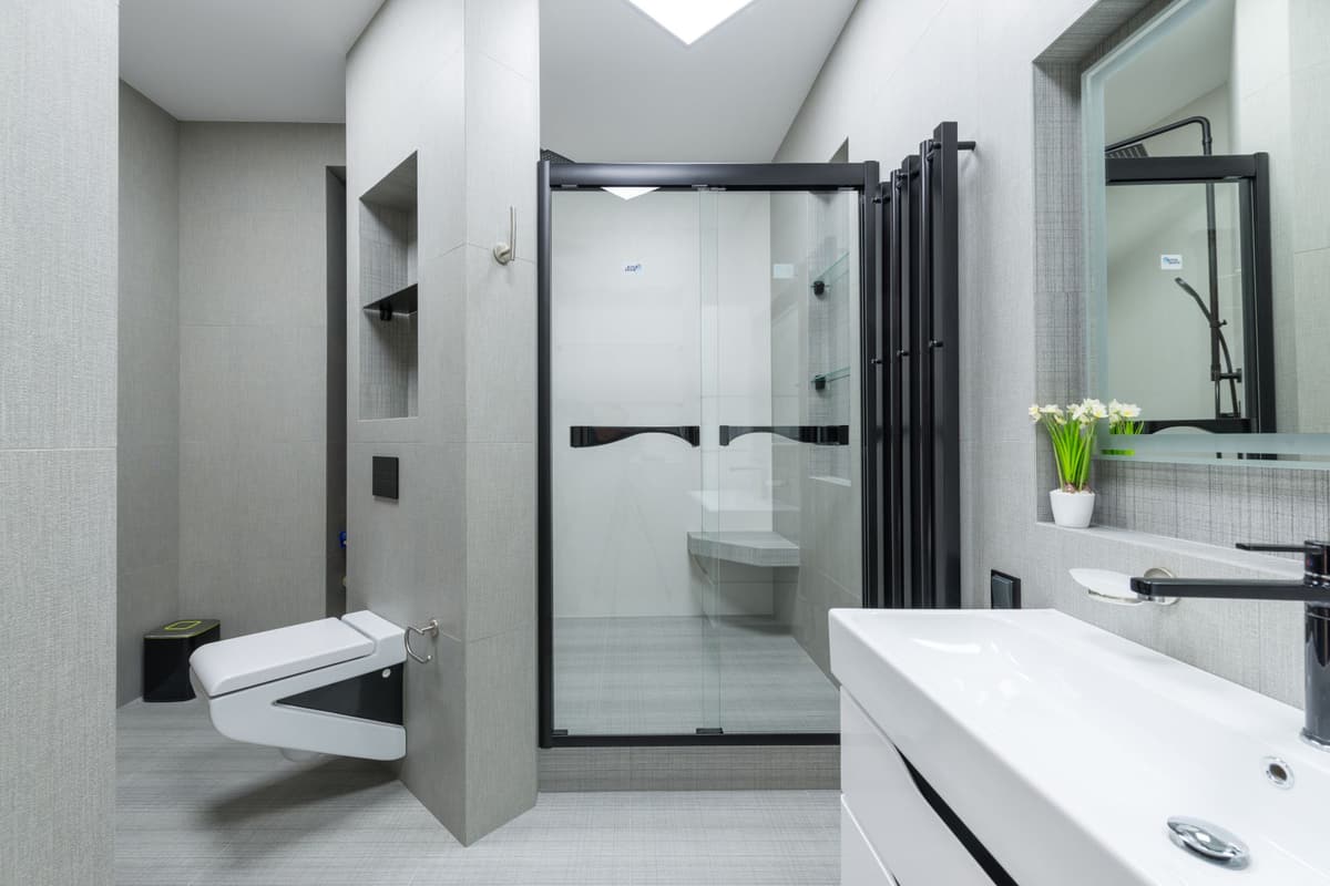Après travaux : salle de bain rénovée blanche avec douche vitrée, WC suspendu et meuble vasque