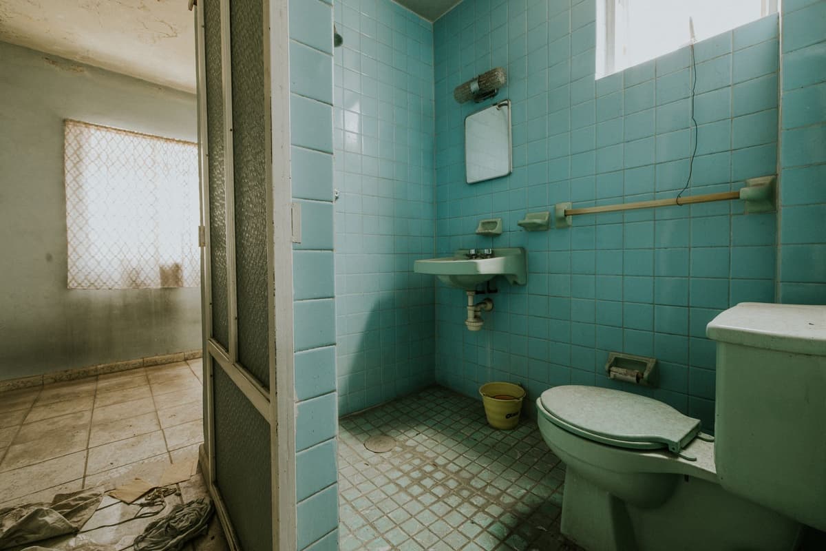 Avant travaux : salle de bain vétuste au carrelage turquoise défraîchi et sanitaires anciens