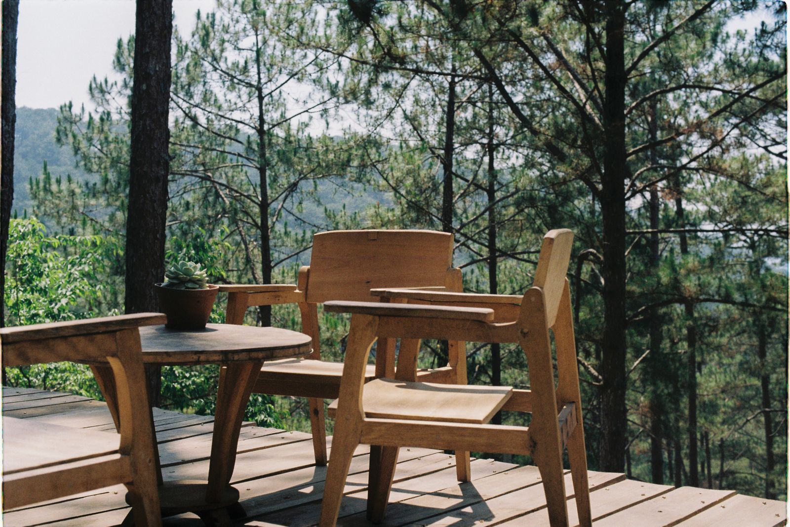 Table et chaises en bois sur une terrasse, vue sur la campagne