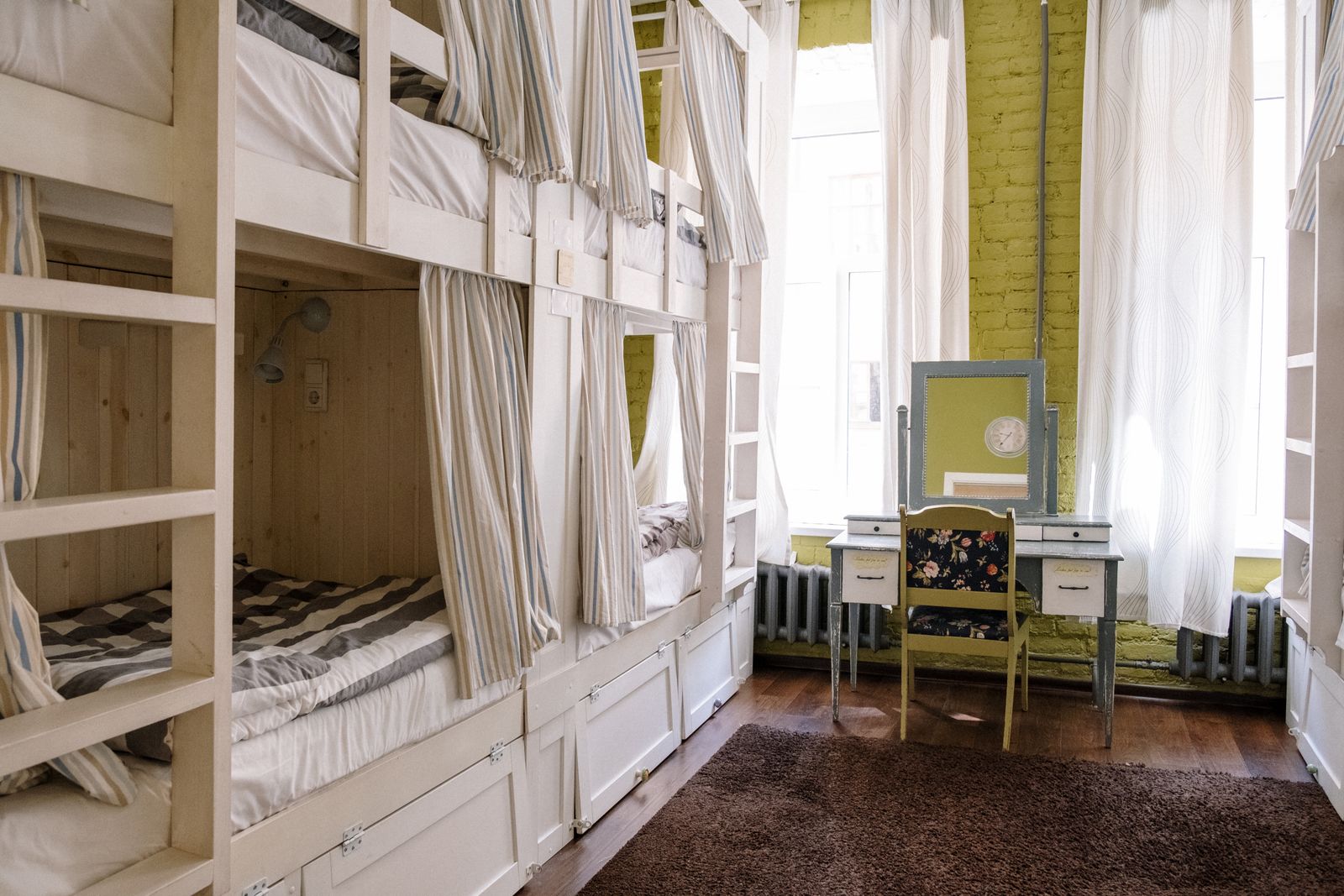Dortoir clair aux lits superposés blancs avec rideaux, bureau près de la fenêtre
