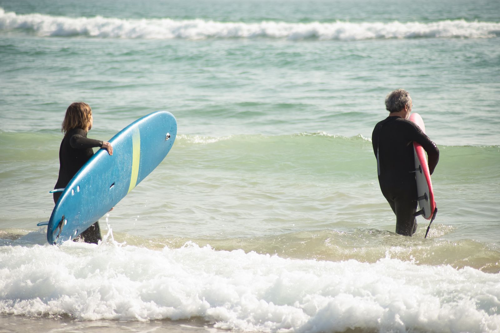 Deux surfeurs entrant dans l’eau avec leurs planches