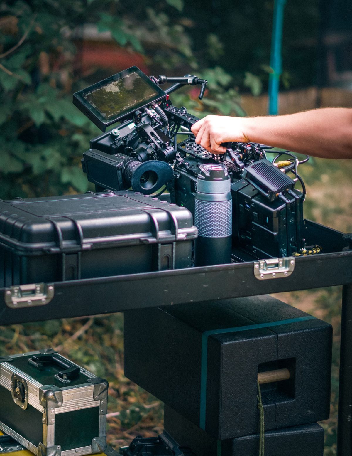 Main réglant une caméra cinéma posée sur sa valise