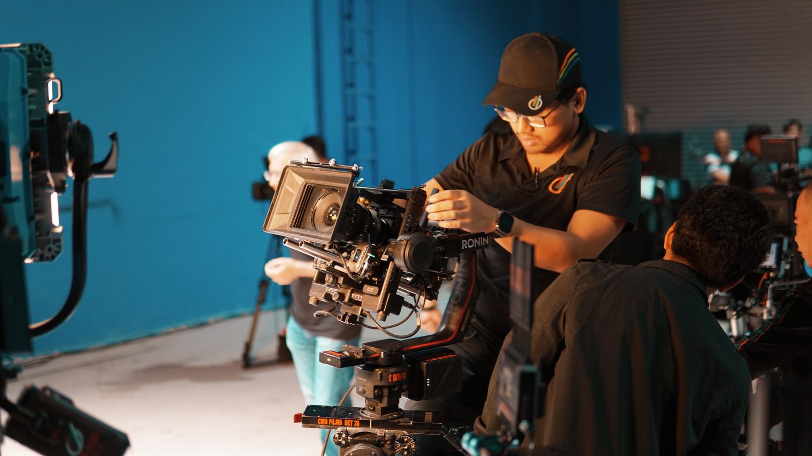 Opérateur réglant une caméra cinéma dans un studio bleu