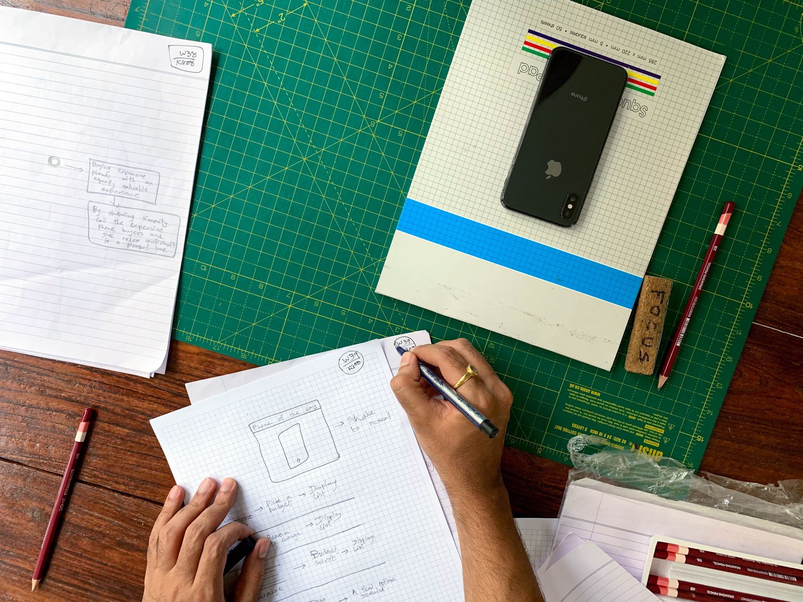 Croquis d’écrans à la main sur papier quadrillé, téléphone posé à côté