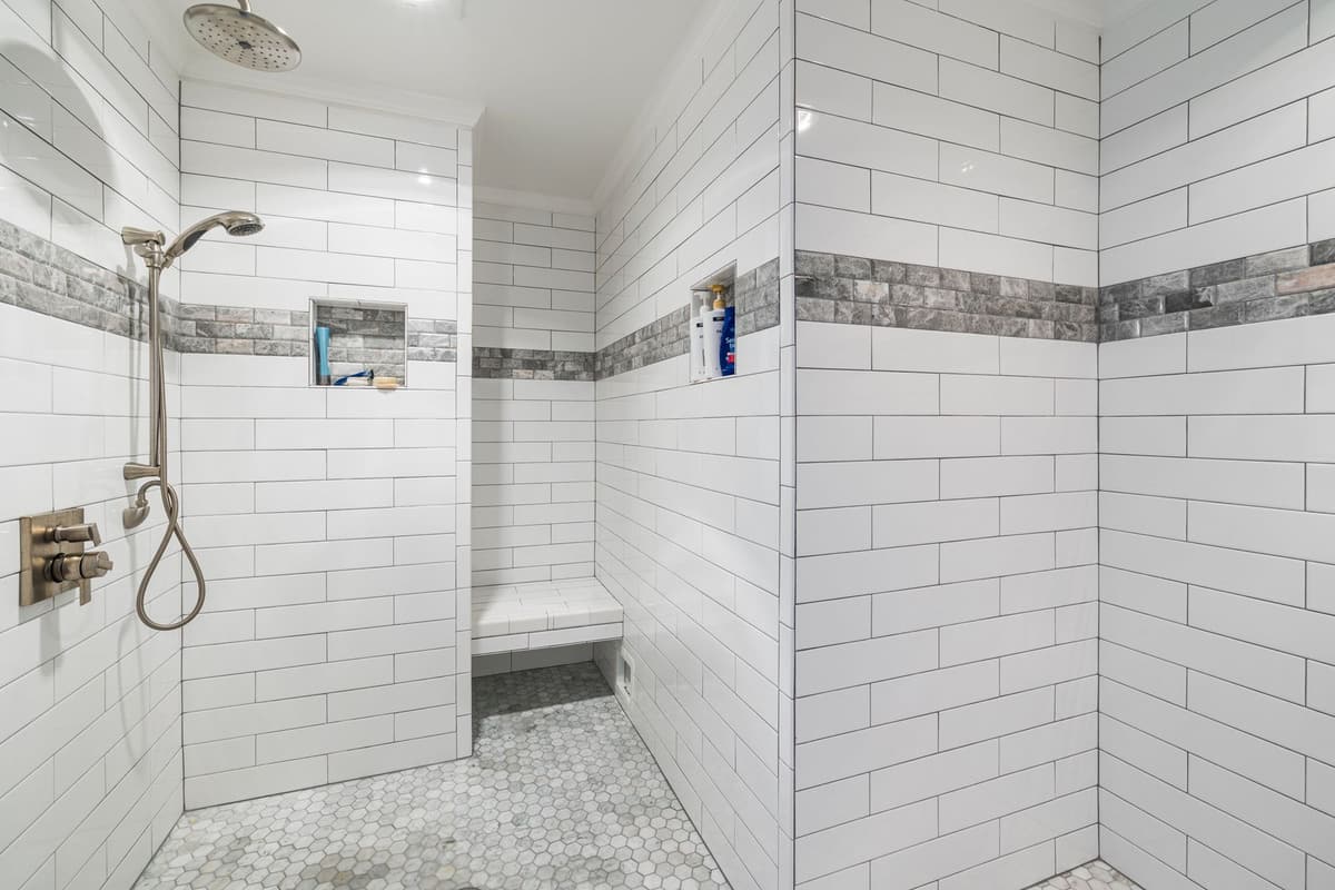 Douche à l'italienne carrelée en faïence blanche avec banc maçonné et sol en mosaïque
